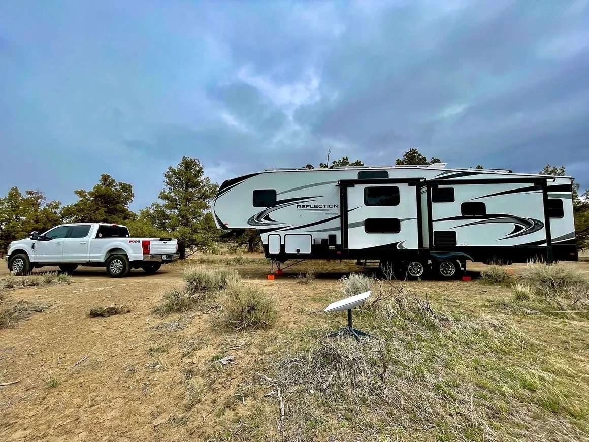 A truck and trailer parked in the grass.