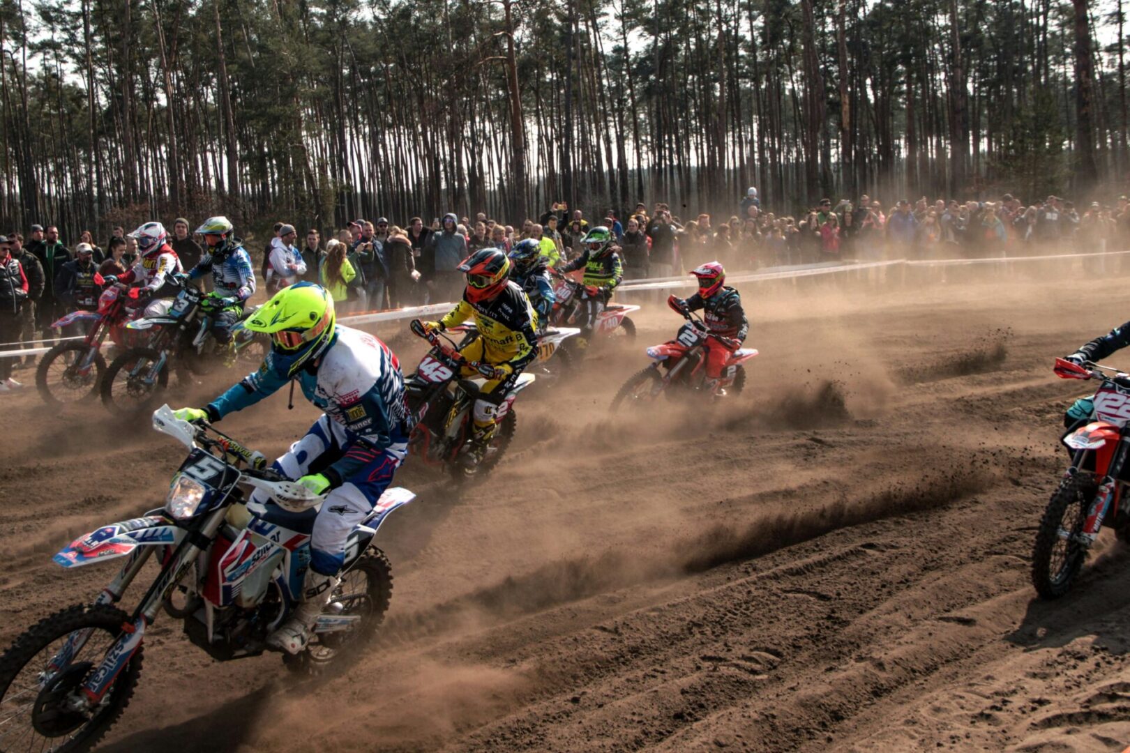 A group of people riding motorcycles on dirt road.